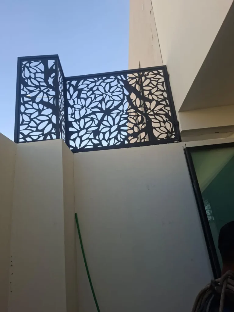 ساتر حديد مقصوص بنقشة أوراق أشجار فوق جدار سطح منزل