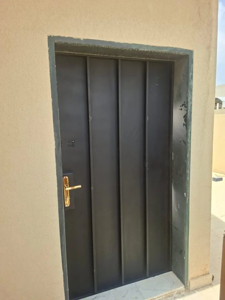 باب حديد أسود بخطوط طولية بارزة ومقبض ذهبي