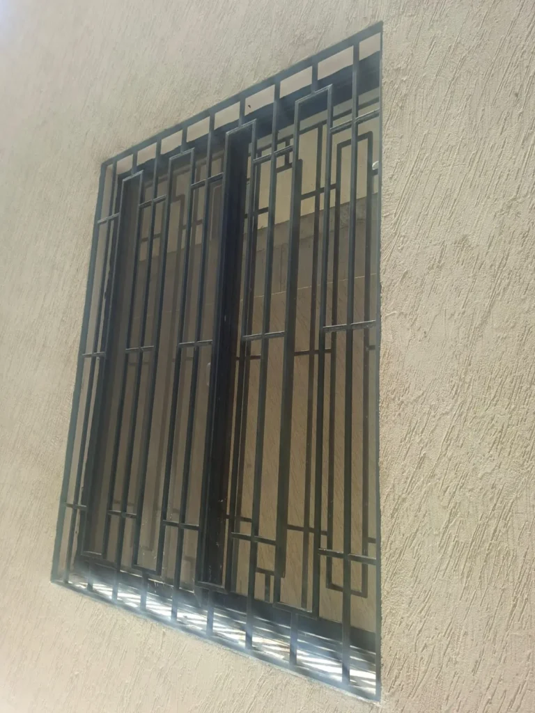 شبك حماية حديد بتصميم هندسي على نافذة