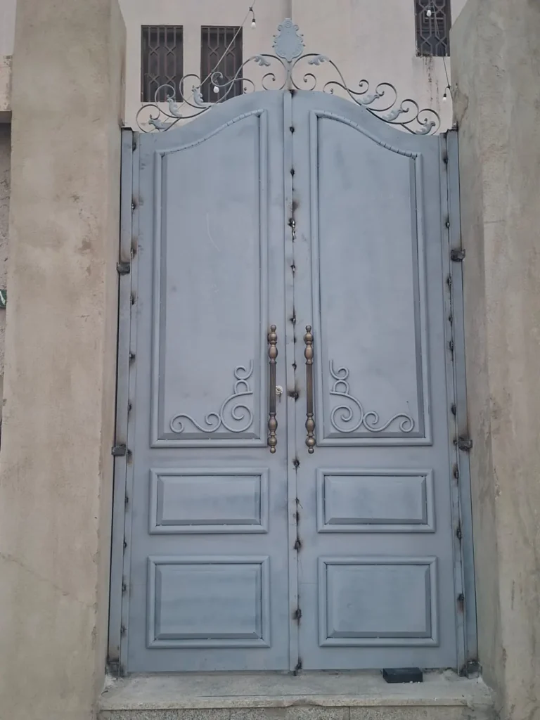 بوابة حديد مزدوجة بألواح بارزة وزخرفة علوية